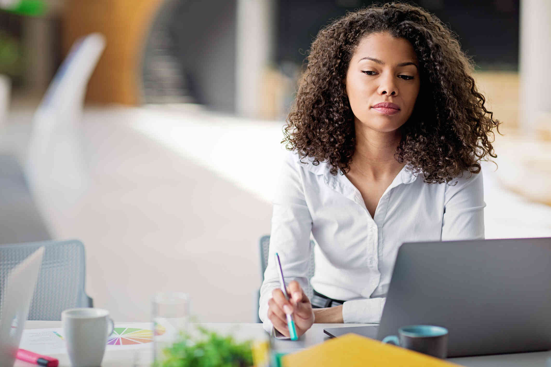 A woman seated at her desk gazes blankly, distracted by her thoughts.